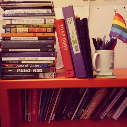 bright stack of books and a pride flag